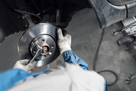 80736887 Car Mechanic Hands Replace Brakes In Garage